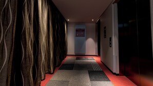 Un pasillo con cortinas estampadas, piso alfombrado y un ascensor.