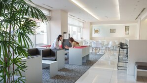 Un espacio de oficina moderno con cubículos, una planta grande en maceta y un interior luminoso y bien iluminado.