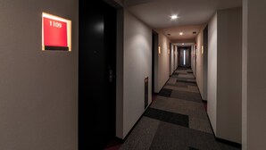 Un pasillo de hotel con suelo alfombrado, un cartel que indica la habitación 1109 y varias puertas a lo largo del pasillo.