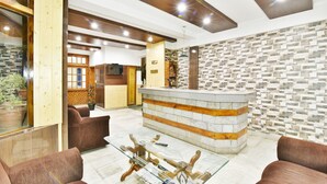 A lobby with a reception desk, seating area, and a stone-patterned wall. - Hotel Devlok (Manali)