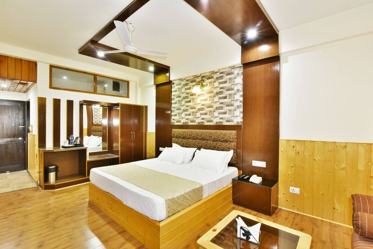 Una habitación de hotel moderna con una cama de madera, un escritorio, un armario y un espejo.