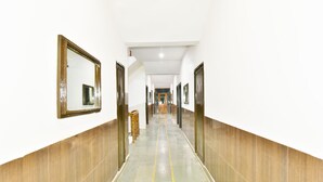 A long, narrow hallway with wooden paneling on the walls and a tiled floor. - Hotel Devlok (Manali)