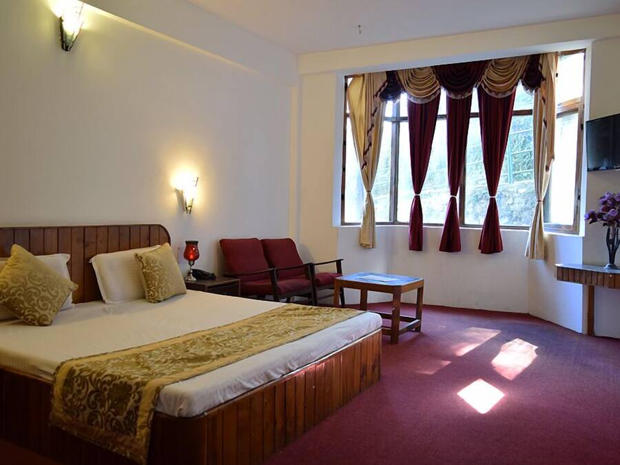 Una habitación de hotel con una cama grande, un escritorio, una silla y un televisor montado en la pared.