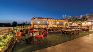 An outdoor dining area with tables and chairs, a covered seating area, and a bar.