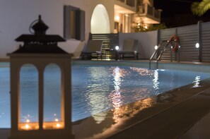 Una piscina con una linterna, sillas y una escalera que lleva a una zona iluminada.