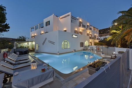 Una piscina al aire libre, sombrillas, sillones reclinables de piscina