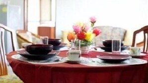 A dining table set with plates, bowls, and a vase of flowers. - Poonchock Mansion (Bangkok)