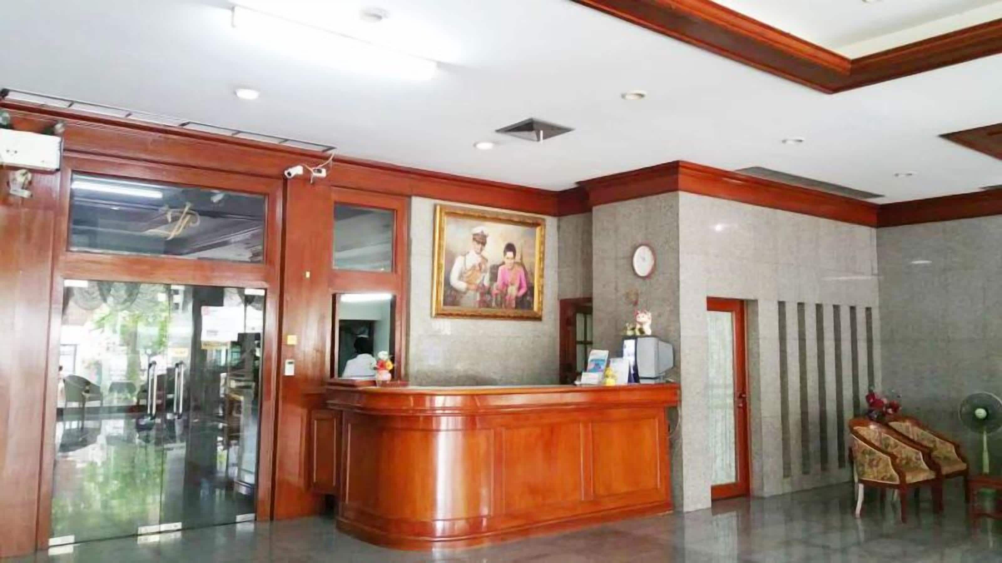 A reception area with a wooden reception desk, a framed picture on the wall, and a clock.
