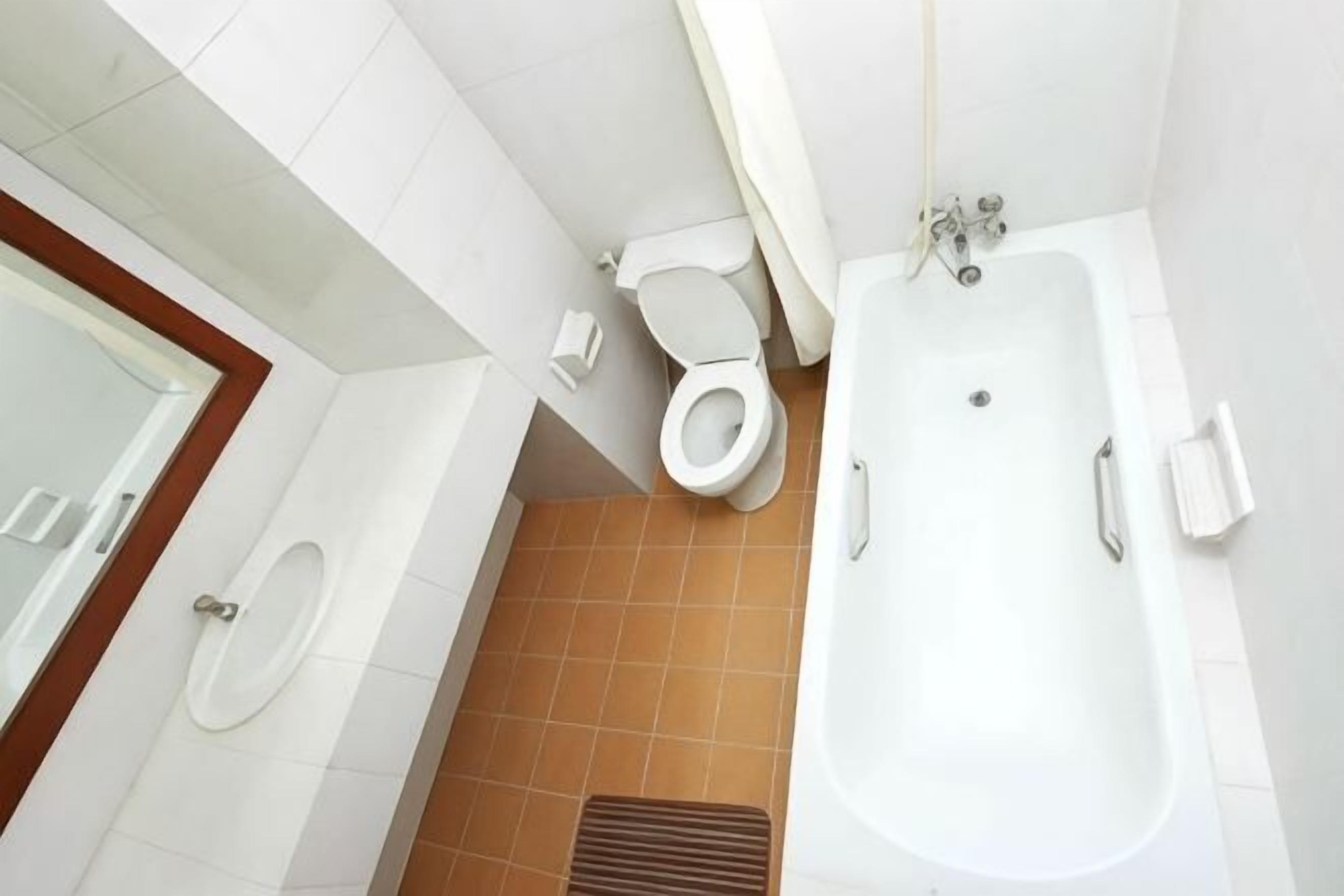 A bathroom with a toilet, bathtub, and a shower area.