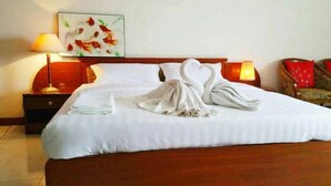 A neatly made bed with white linens and two towels arranged in a heart shape. - Poonchock Mansion (Bangkok)