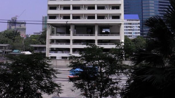A multi-story building with a prominent sign displaying a phone number. - Poonchock Mansion (Bangkok)