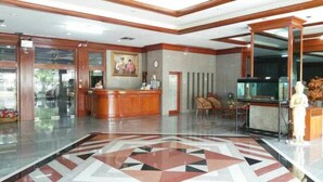 A hotel lobby with a reception desk, a patterned floor, and a statue. - Poonchock Mansion (Bangkok)