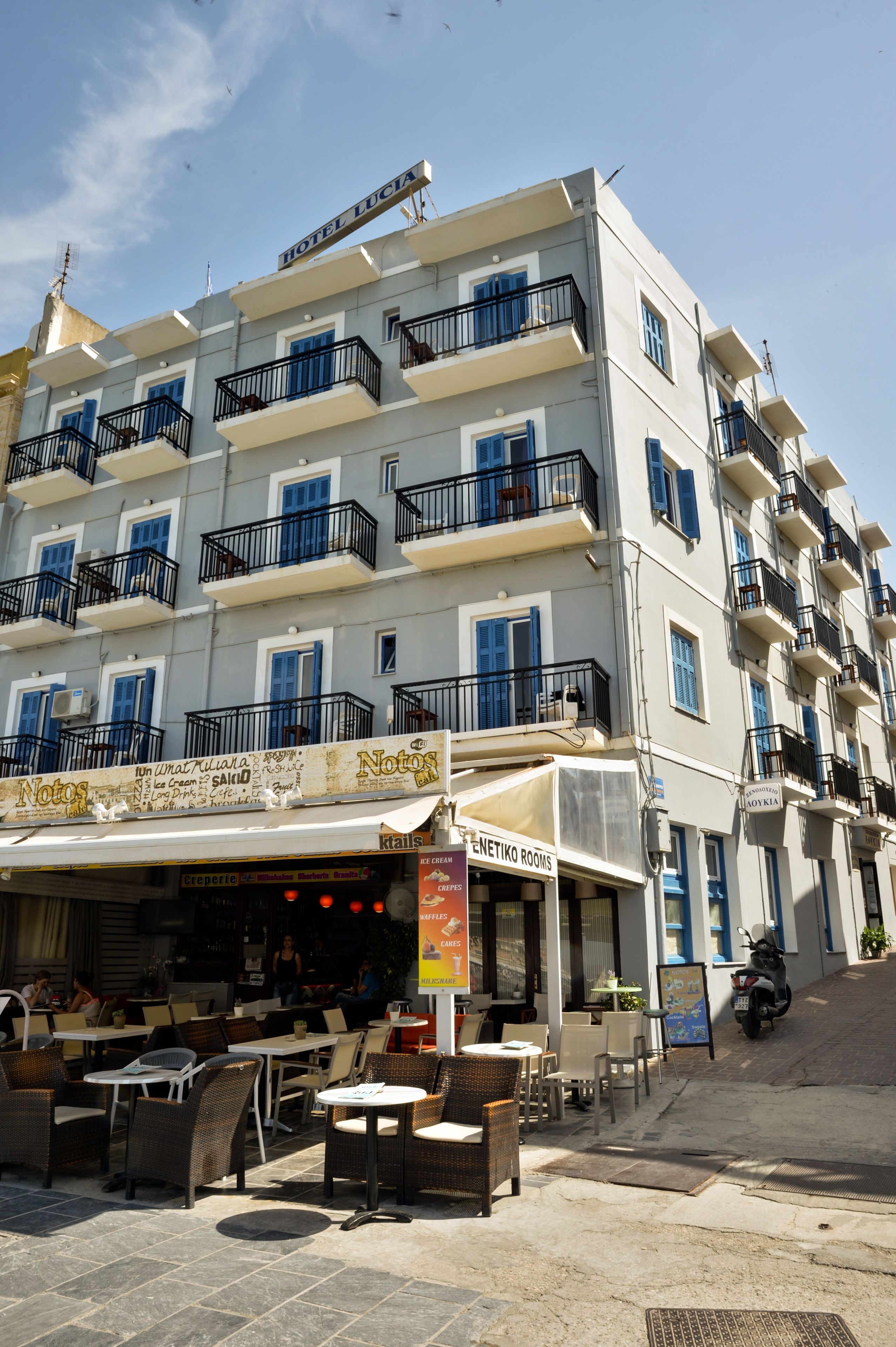 A multi-story hotel with balconies, outdoor seating, and a sign for 'Hotel Lucia'.