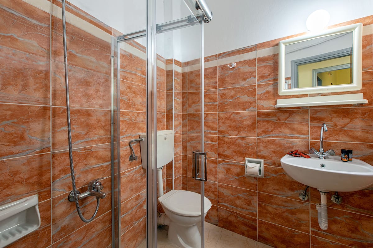 A bathroom with a glass-enclosed shower, a toilet, and a sink with a mirror above it.