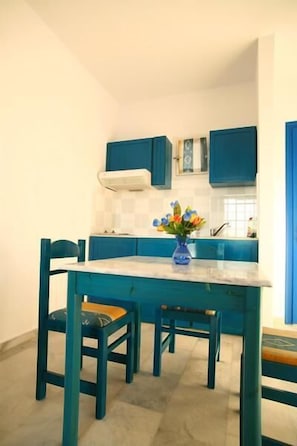 A kitchen with teal cabinetry, a white countertop, and a vase with flowers.