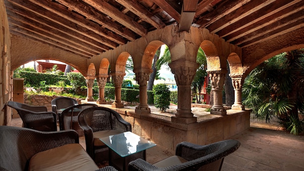 An outdoor patio with stone columns, wicker furniture, and a glass table. - Bonanza Park Hotel by Olivia Hotels Collection (Calvia)