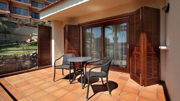 A balcony with a table and chairs, a sliding glass door, and a view of a building with balconies.