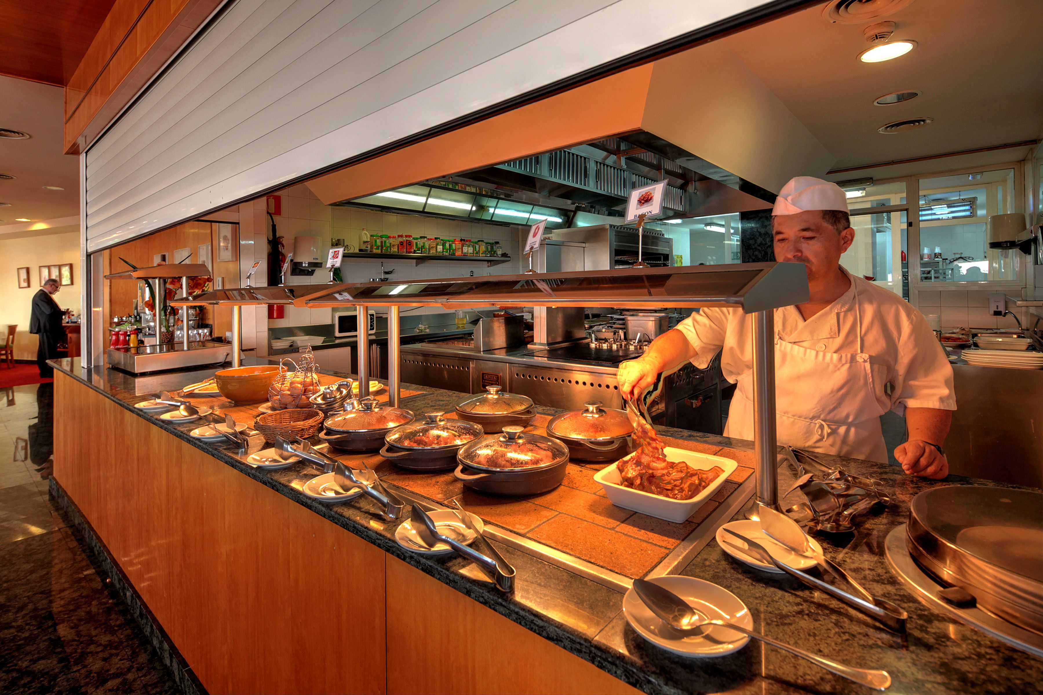 Buffet com diversos pratos e um chefe preparando comida.