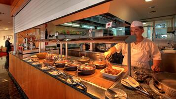 Buffet com diversos pratos e um chefe preparando comida.
