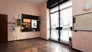 A hotel lobby with a marble floor, a reception desk, a map on the wall, and a large window with curtains. - Residence Lepontina (Milan)