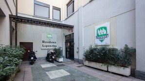 A hotel entrance with a sign for 'Residence Lepontina' and 'Mirage Hotel'. There are potted plants and a motorcycle parked outside. - Residence Lepontina (Milan)