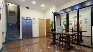 A lobby with a marble floor, a reception desk, a staircase, and an elevator. - Residence Lepontina (Milan)