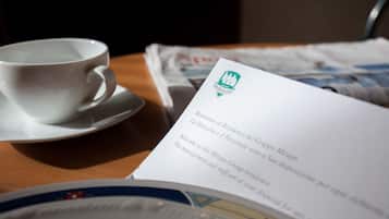 Une tasse de café posée sur une soucoupe, un menu et une assiette ornée de motifs floraux.