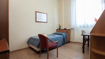 Una stanza con un letto, una scrivania, una sedia e una finestra con tende.
