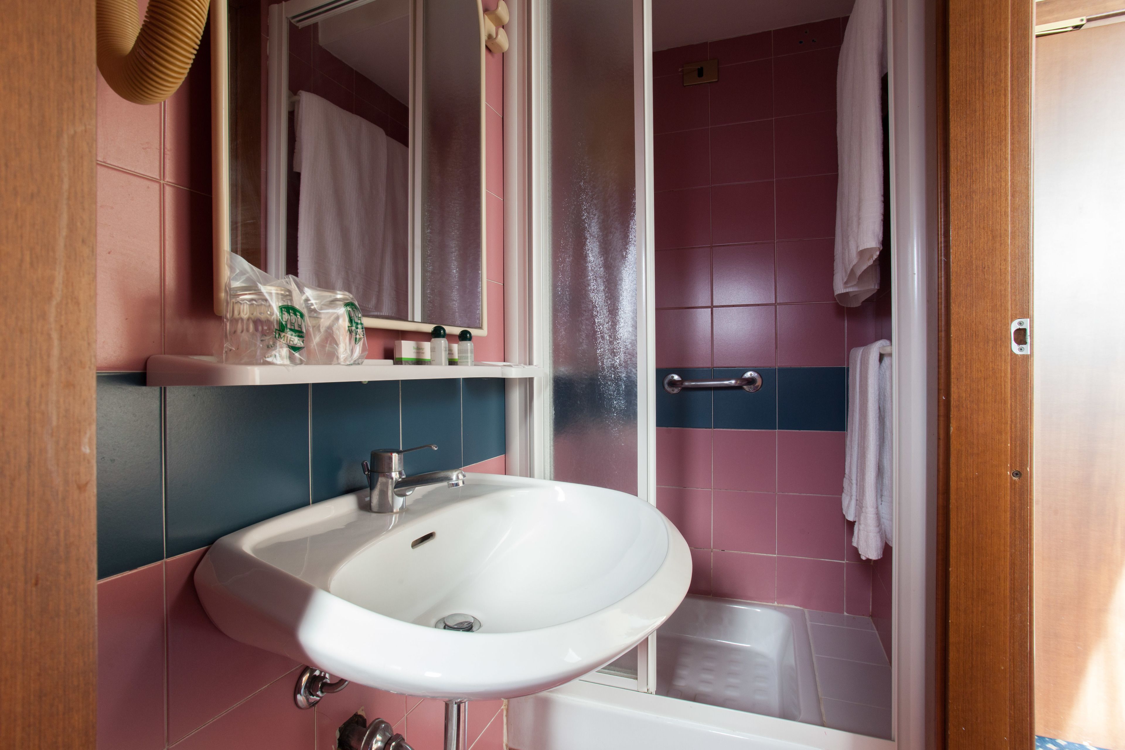 Un baño con lavamanos blanco, espejo y zona de ducha.
