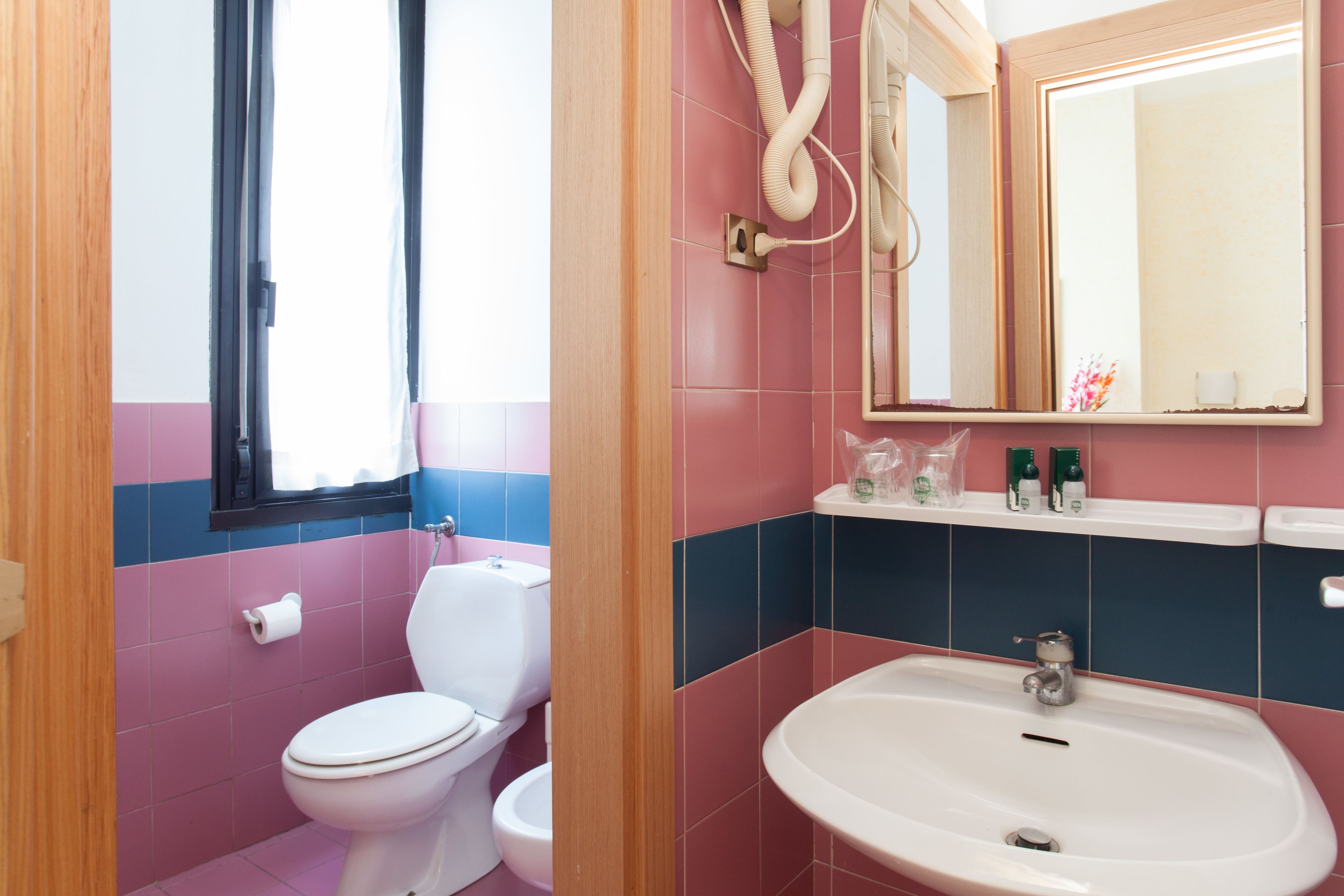 A bathroom with a toilet, sink, and mirror.