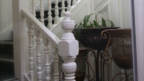 A staircase with white balusters and a handrail, leading to a landing with a potted plant and a decorative mirror. - Fox Connaught (London)