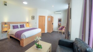 A hotel room with a bed, bedside tables, a desk, a chair, a mirror, and a potted plant. - Fox Connaught (London)
