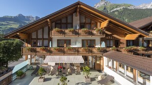 Un hotel de estilo chalé con balcón, mobiliario exterior y vistas a la montaña.
