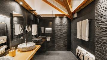 A modern bathroom with a stone sink, wooden vanity, and a stone wall.