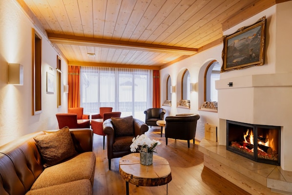 Una sala de estar acogedora con chimenea, sofás de cuero y techo de madera.