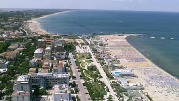 Vista aerea di una città costiera con spiaggia, edifici e una strada.