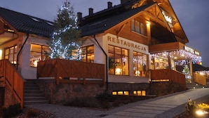 En toetages bygning med restaurant og hotelskilt, træfacade og stensokkel.