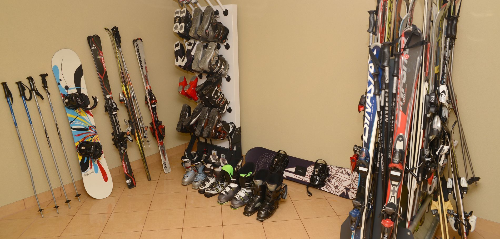Un cuarto de guardado para equipo de esquí con esquíes, bastones y botas organizados en el suelo y en estantes.