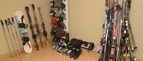 Un cuarto de guardado para equipo de esquí con esquíes, bastones y botas organizados en el suelo y en estantes.