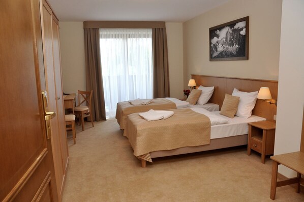 Habitación de hotel con dos camas, un escritorio y una silla.