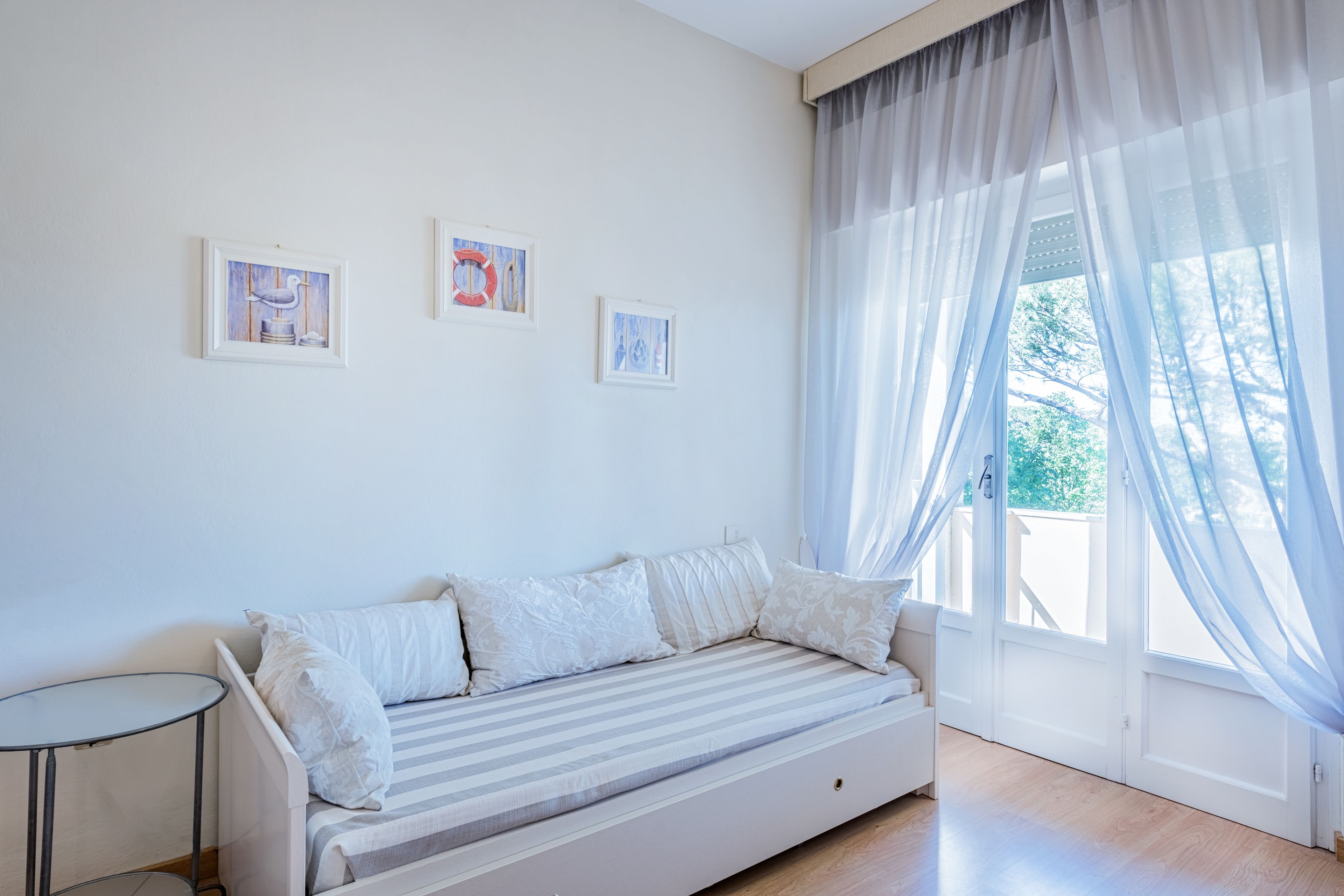 Una habitación con una cama, una mesita pequeña y tres cuadros en la pared.