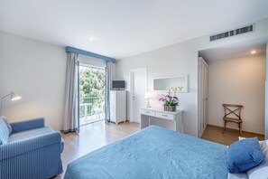 A bedroom with a bed, a desk, a chair, a wardrobe, and a balcony with a view of greenery. - Hotel Andreaneri (Pietrasanta)