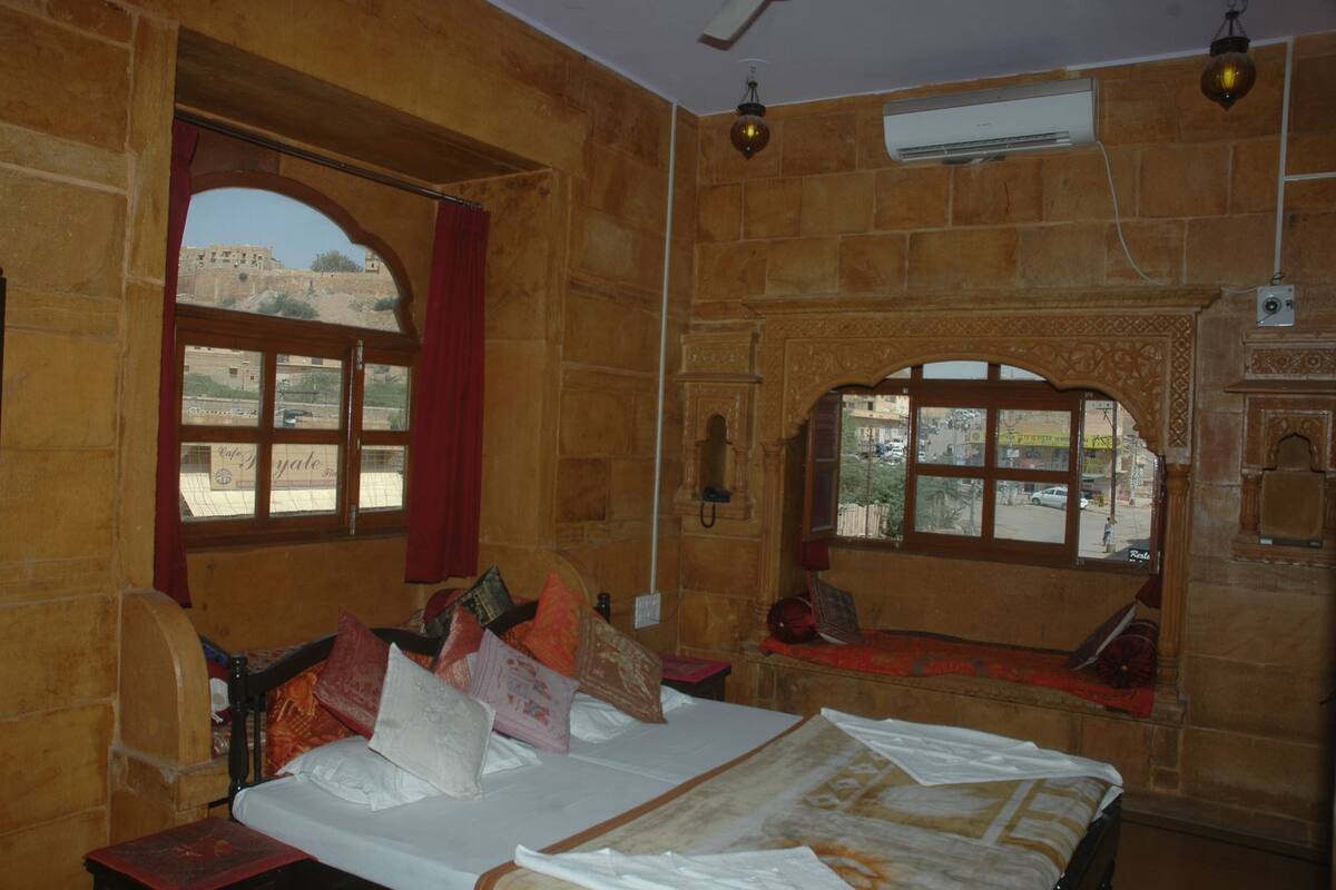 A traditional room with a bed, two windows, and a view of the outside.