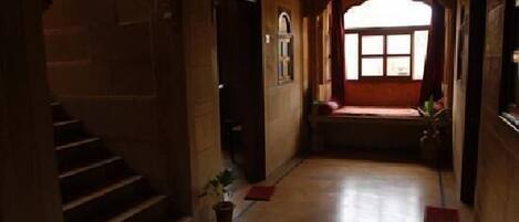 A corridor with a staircase on the left, a window with a view on the right, and a door at the end.