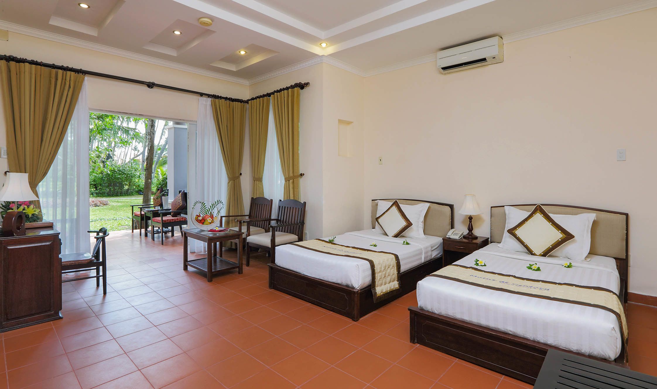 Une chambre d’hôtel avec deux lits, un bureau, des chaises et une vue sur l’extérieur.