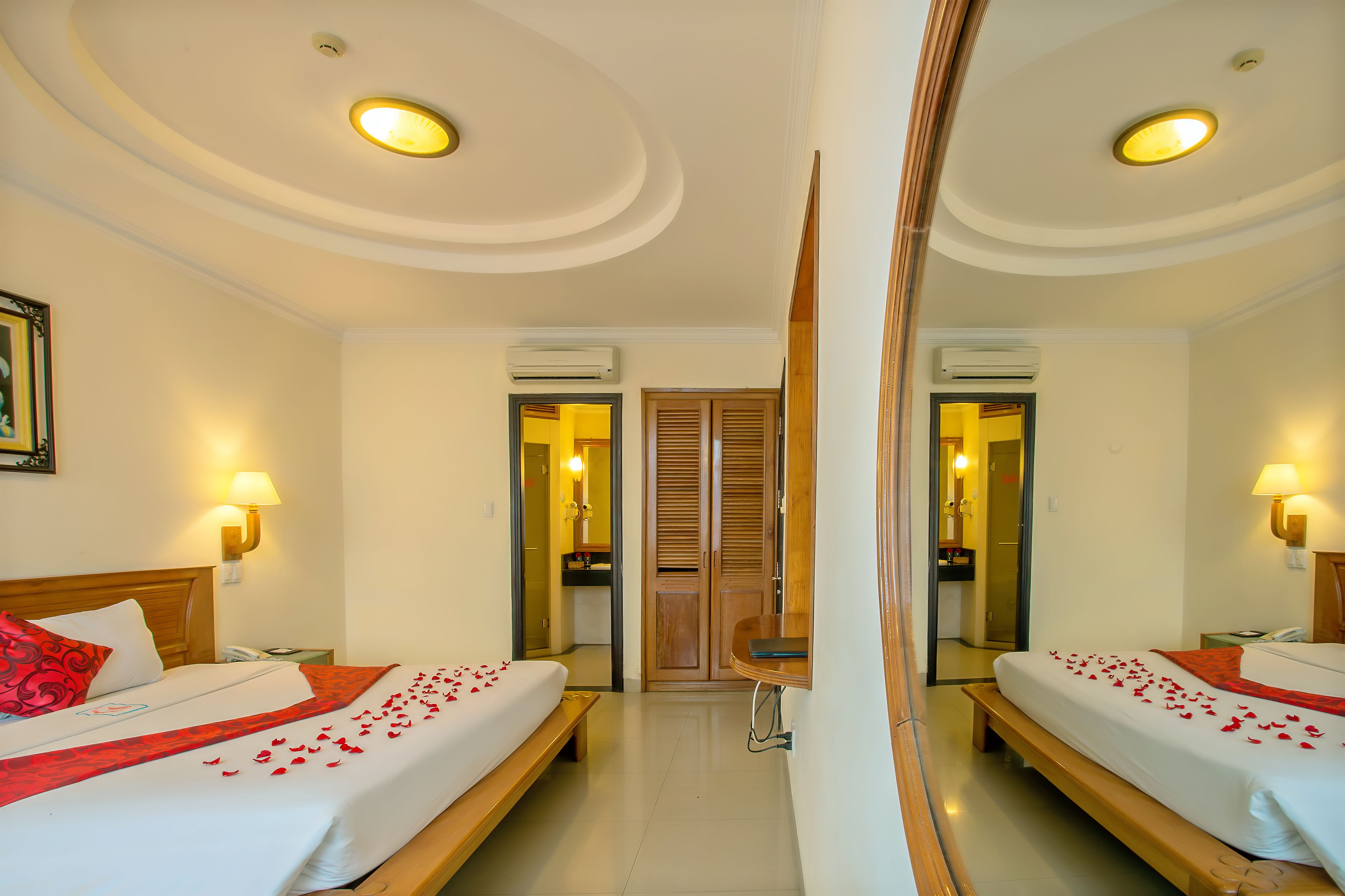 Habitación de hotel con dos camas, un espejo, una mesita de noche, una lámpara y un equipo de aire acondicionado.