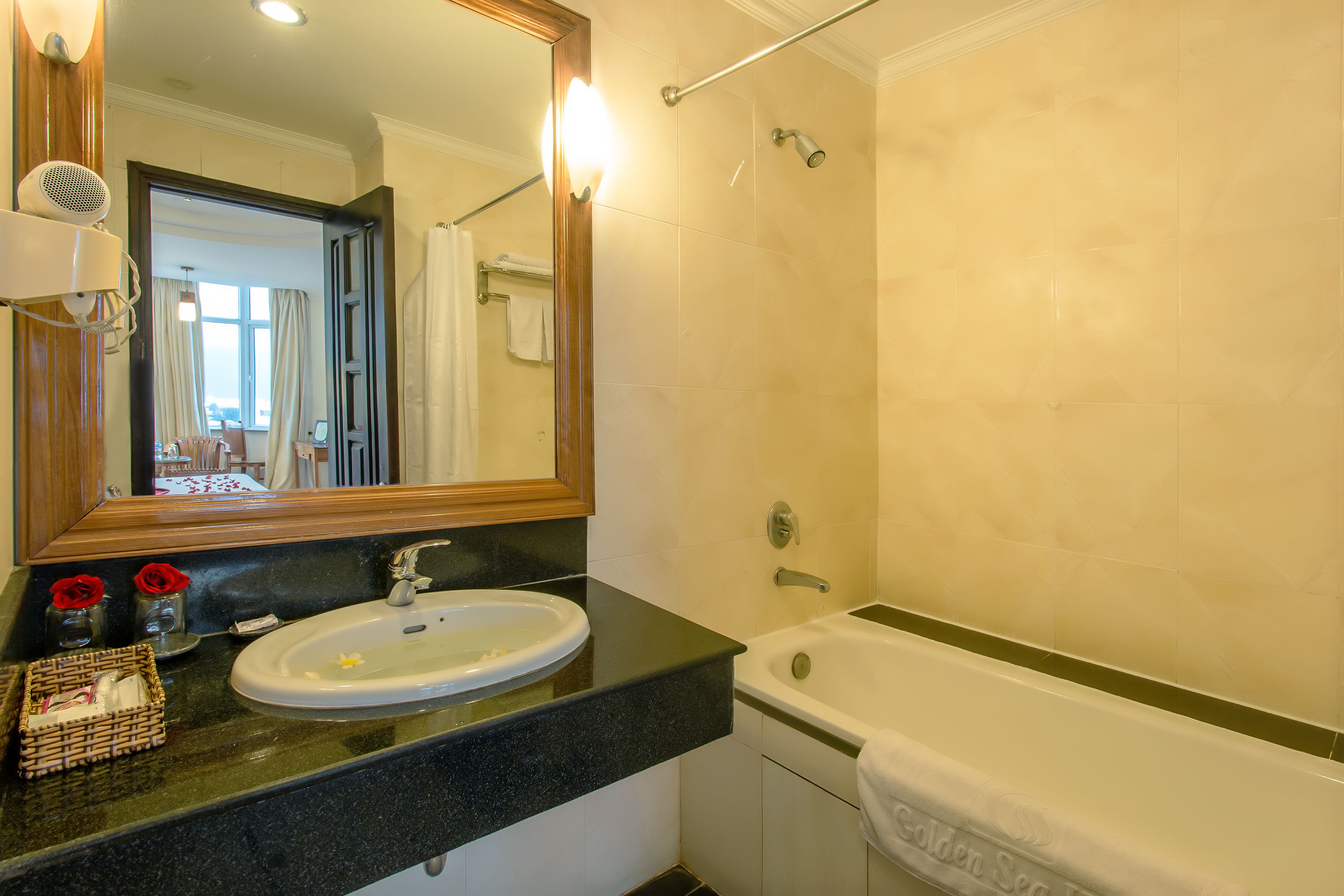 A bathroom with a sink, mirror, and bathtub.