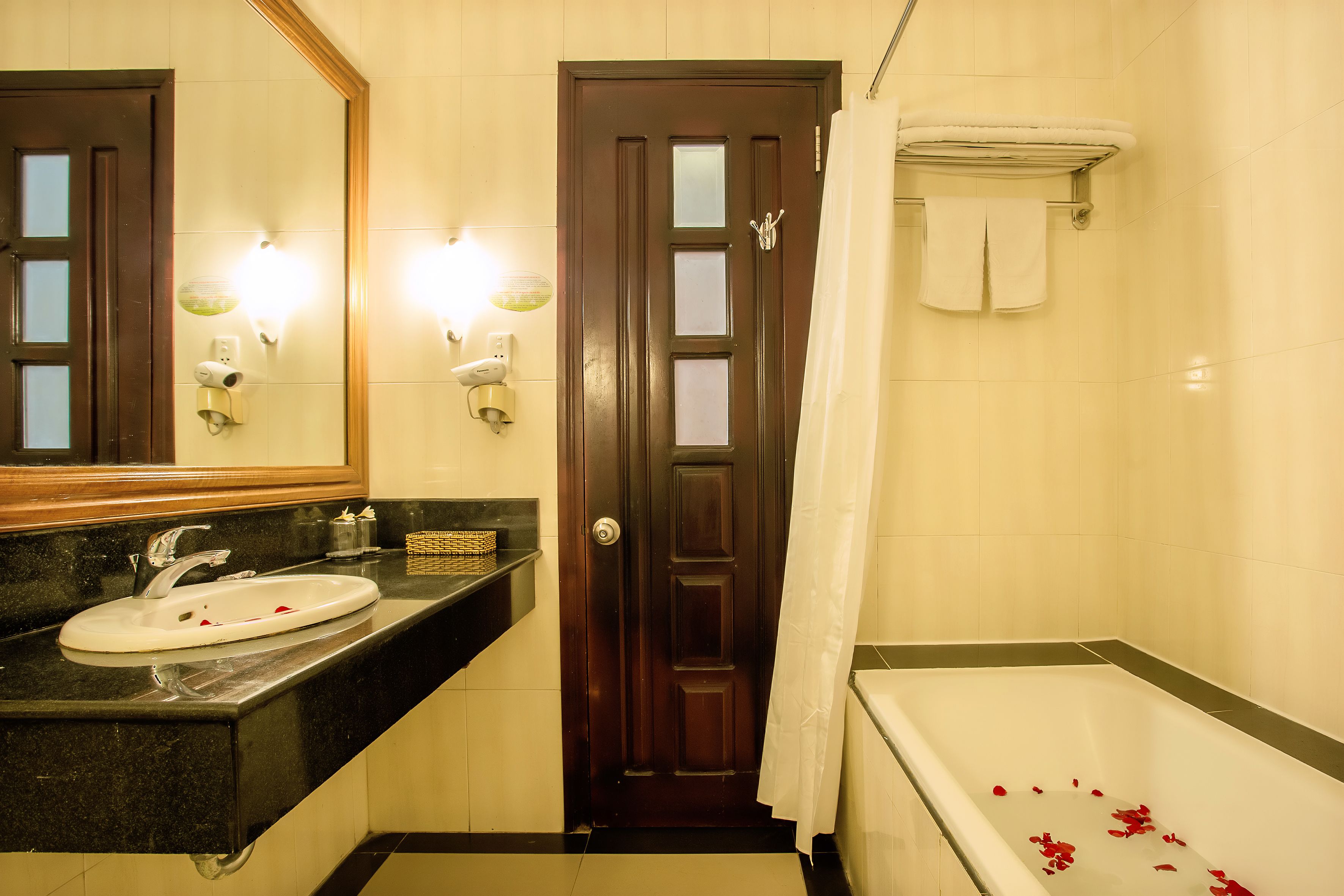 A bathroom with a sink, mirror, shower, and a towel rack.