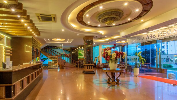 A hotel lobby with a reception desk, a staircase, and a decorative ceiling. - Golden Sea Hotel (Da Nang)