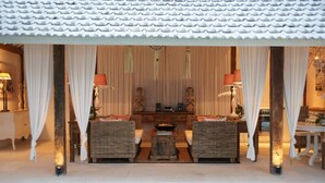 Ein traditionell eingerichteter Raum mit Kachel Decke, zwei Korbschaukelsofas, einem kleinen Tisch und einem dekorativen Altar.